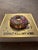 This mixed media piece features a vibrant donut adorned with colorful sprinkles, set against a shimmering gold background....