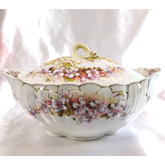 This is a white covered gravy boat or serving dish by Staffordshire. It has white flowers on a purple background with some...