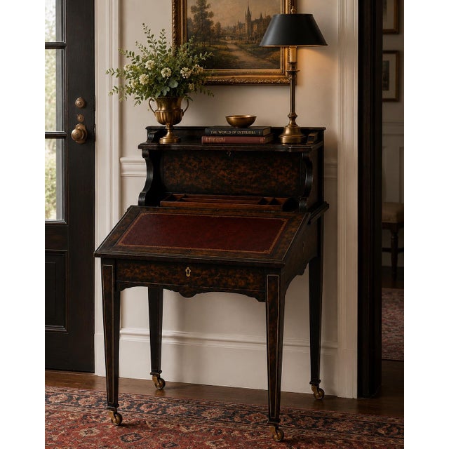 A richly layered Old World-inspired flip-top writing desk finished in a dramatic ebonized burl treatment with oxblood...