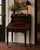 A richly layered Old World-inspired flip-top writing desk finished in a dramatic ebonized burl treatment with oxblood...
