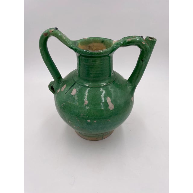 Terracotta jug with spout in handle. Green light and dark glaze, circa 1860. Once a common piece of pottery used daily in...