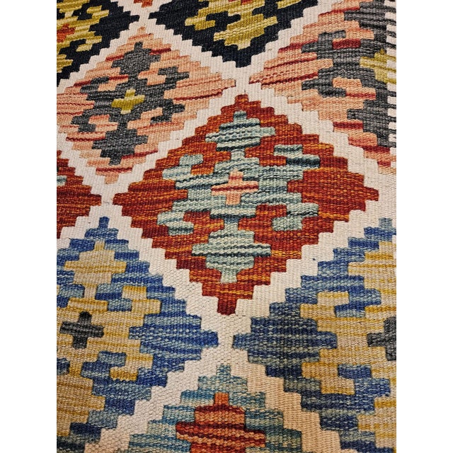 An elegant vintage Afghan kilim, handcrafted from wool, featuring refined tribal geometric patterns and a sophisticated...