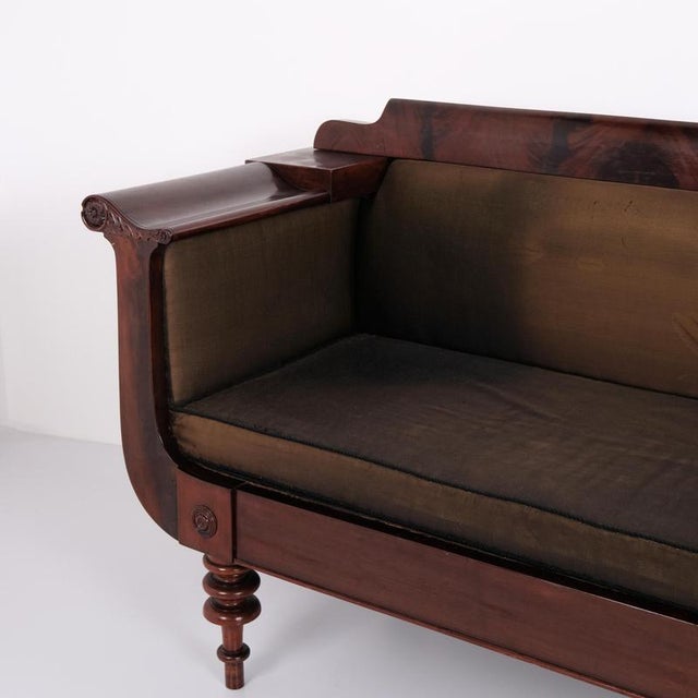 Antique empire sofa from the 1830s, crafted in mahogany with turned legs and brown upholstery. The sofa has a classic...