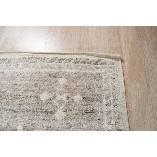 This gray wool rug features a hand knotted pile weave and represents a classic Oushak style. Crafted in India, the rug...