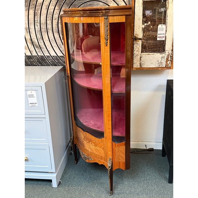 Design Plus Gallery presents a Bow Front Corner Cabinet with a French Style. The solid mahogany case has inlaid treatments...