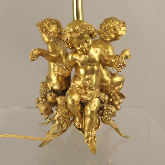 Fire-gilded solid bronze with three celebrating Bacchus putti Putto height: 20 cm Lamp width (bottom): 20 cm Total height...