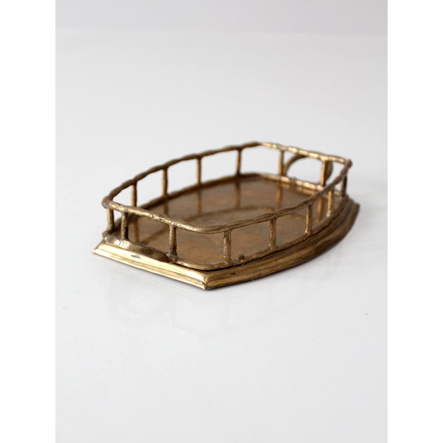 A striking mid-century brass gallery tray featuring a sculptural openwork rail and integrated handles. Its warm brass...
