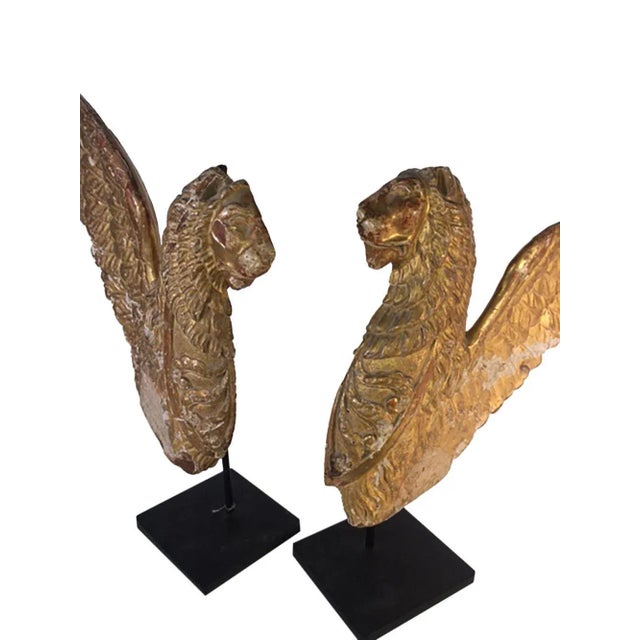 A pair of Italian winged lions carved wood with original gilded finish. Some losses to tips of wings . Circa 1780-1810. On...