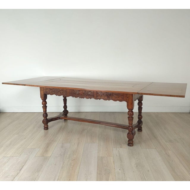 A fruitwood French dining table with two 24" leaves with antique elements. Width measures 68" without leaves.