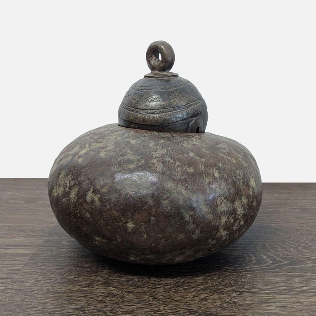 Large cast bronze livestock bell featuring a rounded body, engraved decorative collar, and heavy suspension loop. Rich...