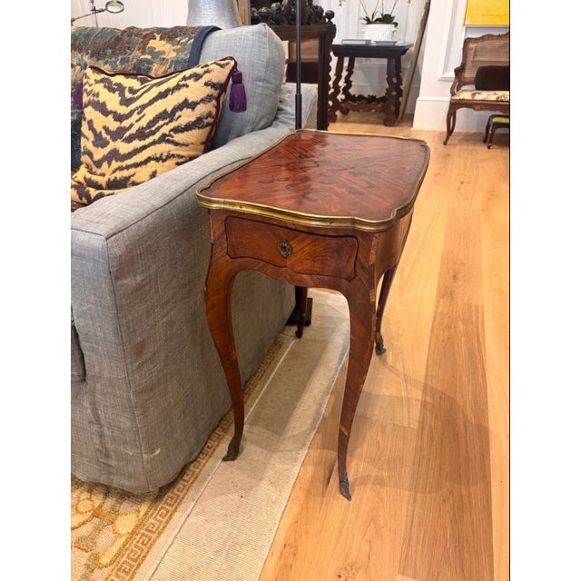 Elegant French Louis XV style side table featuring a shaped serpentine form, graceful cabriole legs, and beautifully...