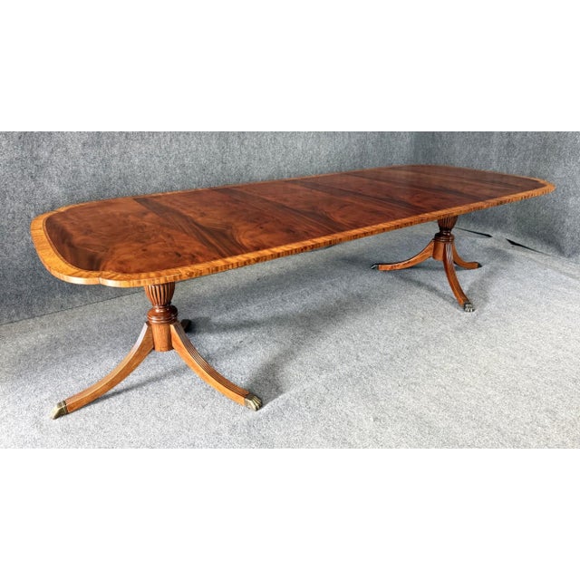 This incredible dining table showcases a stunning flamed mahogany top framed by a finely banded border, with gracefully...