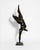 A contemporary figurative bronze of a woman caught mid-leap, body stretched into a single soaring diagonal — legs flung...