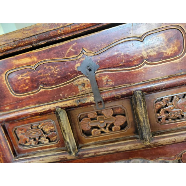 A Chinese lacquered Elm wood side table raised on four rectangular section legs, the body with two long drawers, one with...