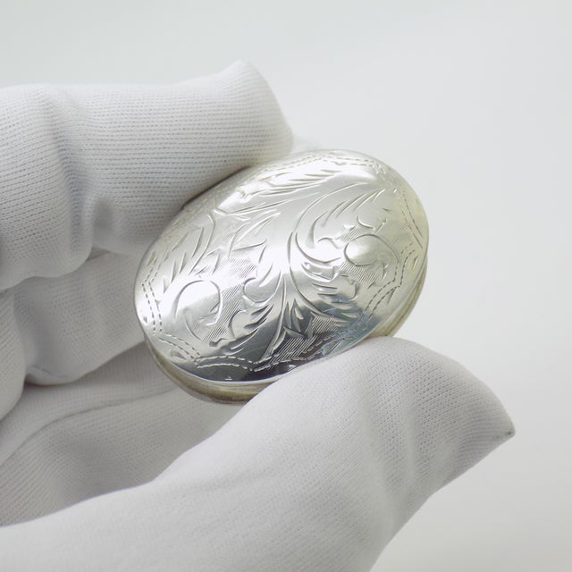 This vintage silver decorative object features an oval form (Scatola Ovale) with a chiseled pattern on the lid....