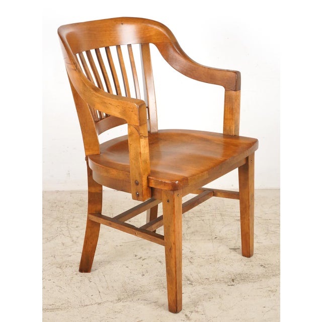 Medium toned wood Arts & Crafts chair with a slated back, high armrests, and box stretchers. There are letters carved on...