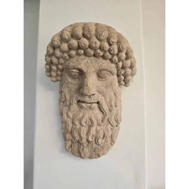This remarkable antique face of a Greek god, crafted from terracotta or a similar material, is a stunning representation...