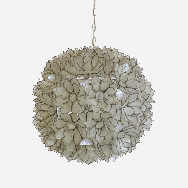 Description Capiz Shell Lotus Pendant Light A spherical pendant with a shade made from layered capiz shell petals arranged...