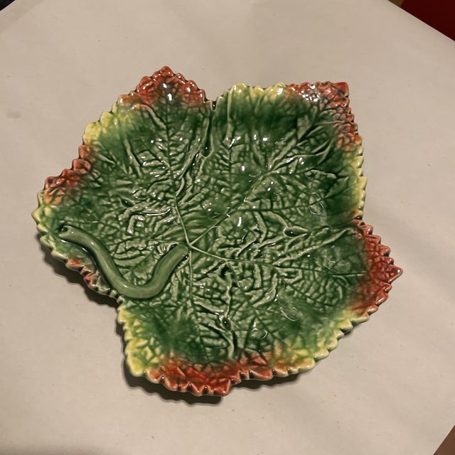 A pretty green, orange, and red majolica leaf plate. This plate will be a fabulous addition to your next dinner party. Use...
