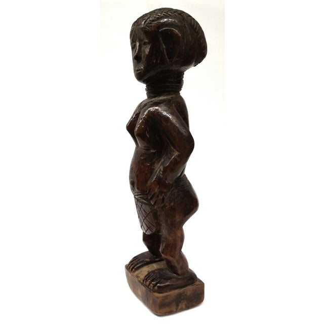 Female figure, Ashanti, Ghana. Standing female ancestor figure with body framed by arms with the hands resting on the...