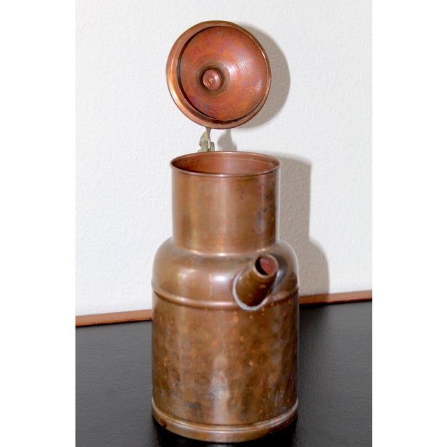 A beautiful vintage hammered copper teapot or pitcher, featuring a classic form with a brass handle and fitted lid....