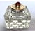 This antique inkwell features a square, cut crystal base paired with a silver and brass hinged lid.The lid is adorned with...