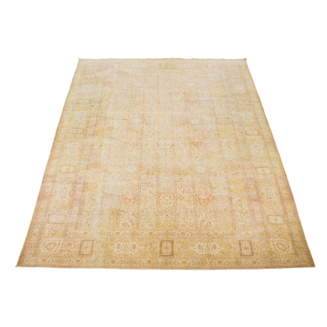 This handcrafted Persian Tabriz wool rug features a traditional floral pattern. The contrast between the beige background...