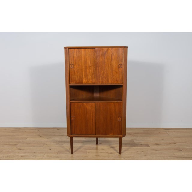 This corner teak chest of drawers was manufactured in Denmark in the 1960s. The chest of drawers features sliding doors,...