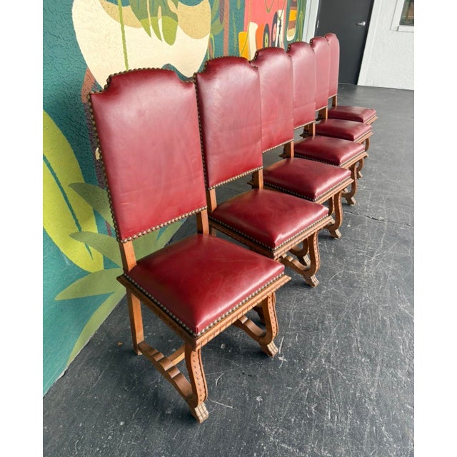 Masterfully carved oak frames with claw feet, ridged legs, red leather, and nailhead trim. This sextet has perfect...