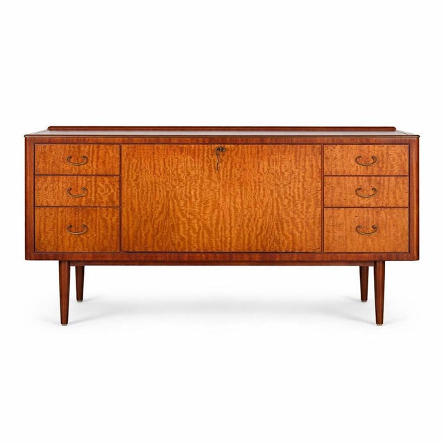 A striking mid century sideboard by Greaves & Thomas, combining beautifully figured rosewood with warm teak tones in a...