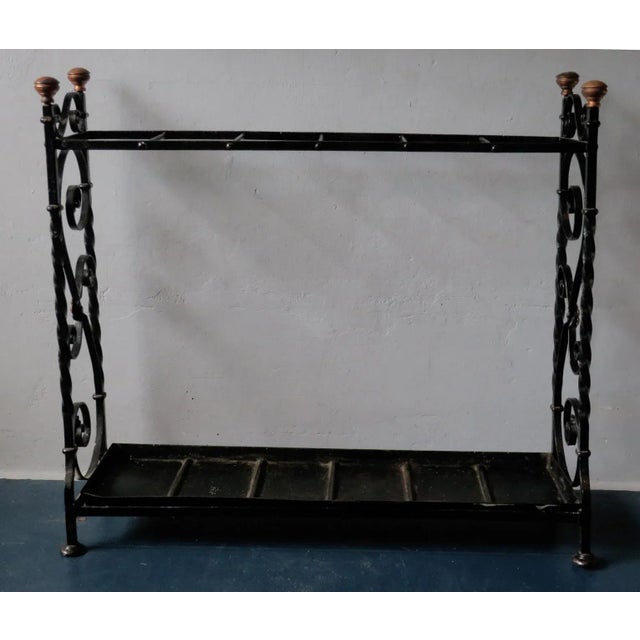 Antique wrought iron umbrella stand with brass finials and feet, dating from about 1890. Patinated brass and iron,...