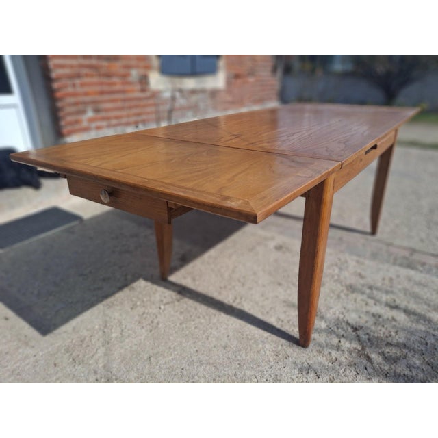 A superb 1950s solid oak dining table, a testament to the craftsmanship of french cabinetmaking in the post-war era. Its...