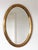 A beautiful vintage pair of gilded oval mirrors in gold from Deknudt mirrors Belgium. Carved wood and beveled glass....