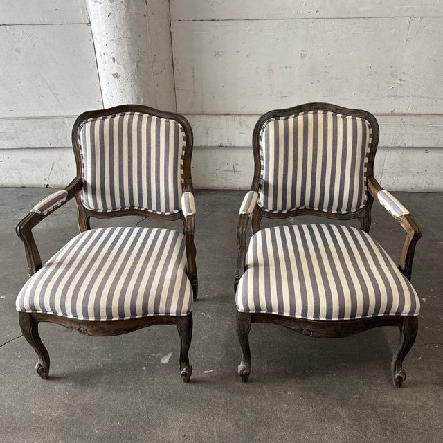 Design Plus Gallery presents a Pair of French Louis XV Style Striped Armchairs. The chairs showcase carved wood frames...