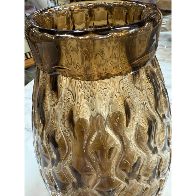 Charming amber glass vase featuring a diamond-patterned textured surface that catches and reflects light beautifully. The...