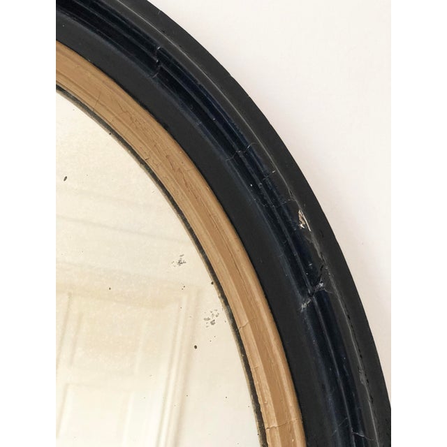 Large Antique French Louis Philippe oval mirror, dating to the late 19th century. The mirror features a black-painted...