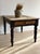 This antique English table features a single drawer with its original brass cup pull and a top of wide boards marked by a...