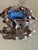 This 1970s Hollywood Regency brooch features a large emerald cut tanzanite-colored center stone framed by sculptural...