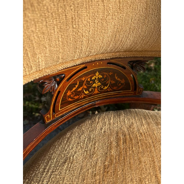 An elegant antique Victorian settee featuring a beautifully detailed wooden frame, turned legs, and decorative inlaid...