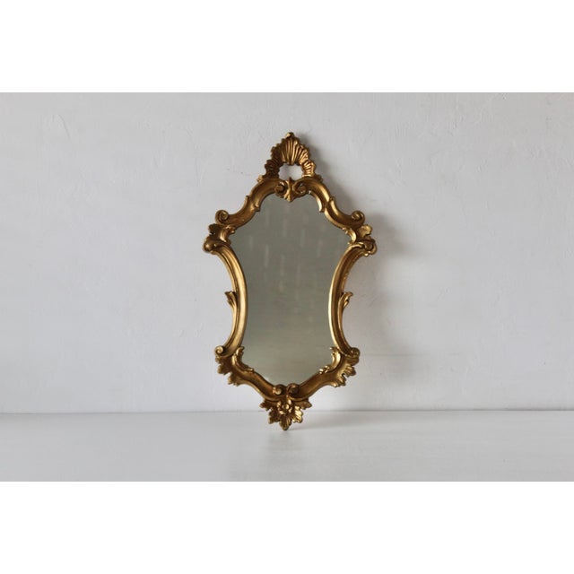 An Italian Rococo–style giltwood style molded acrylic polymer wall mirror. Richly styled with scrolling acanthus and shell...