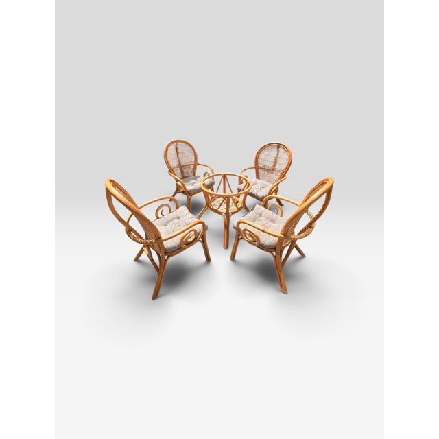 Beautiful vintage five-piece rattan and bamboo dining set featuring four matching high-back armchairs and a sculptural...