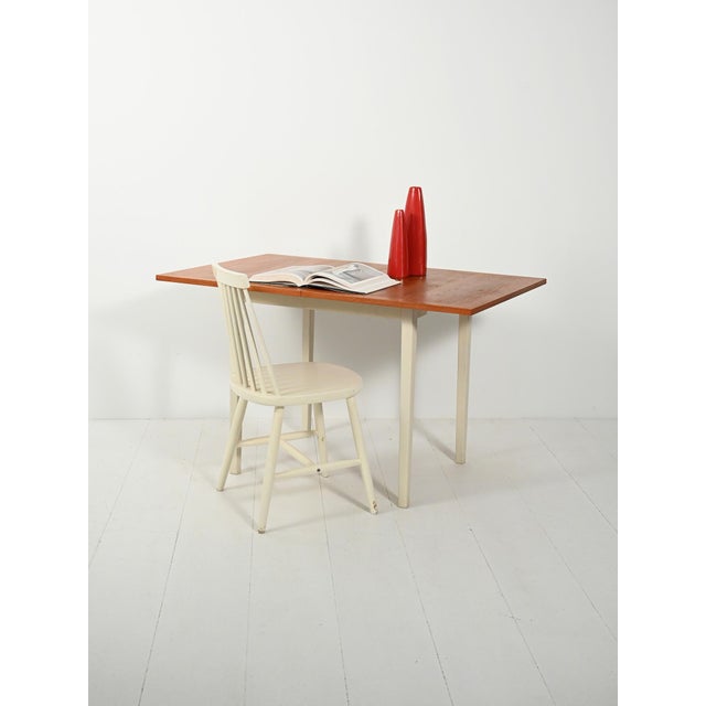 Warm teak top with sliding and swivel mechanism; white lacquered frame and clean lines with a Nordic feel. Elegant lines...