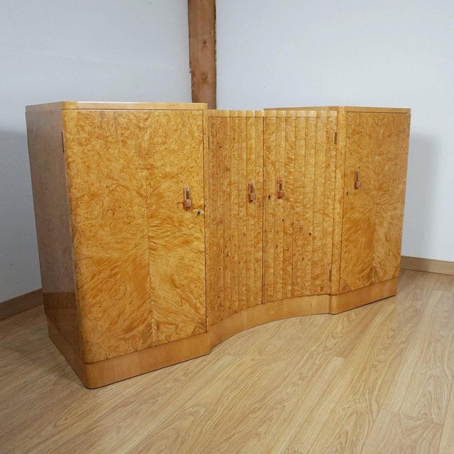 An Art Deco sideboard by Harry & Lou Epstein. Bleached burr walnut veneered on solid mahogany with mahogany lined drawers...