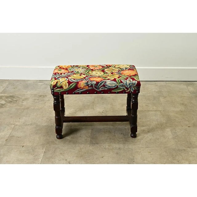 This comfortable French oak and tapestry stool from the 19th century is upholstered in a colorful floral needlepoint...