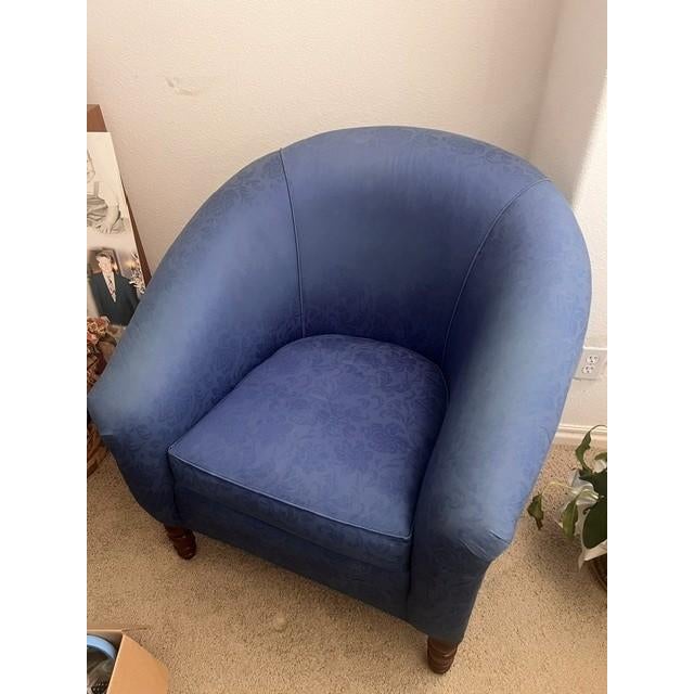 This is a classic barrel-style tub chair featuring a rounded, continuous back and armrest design. It is upholstered in a...