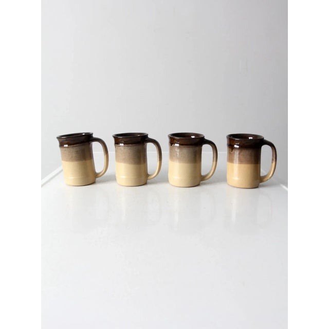Cozy up with this is a set of four vintage studio pottery mugs. The handmade ceramic mugs feature a tri-tone glaze of...