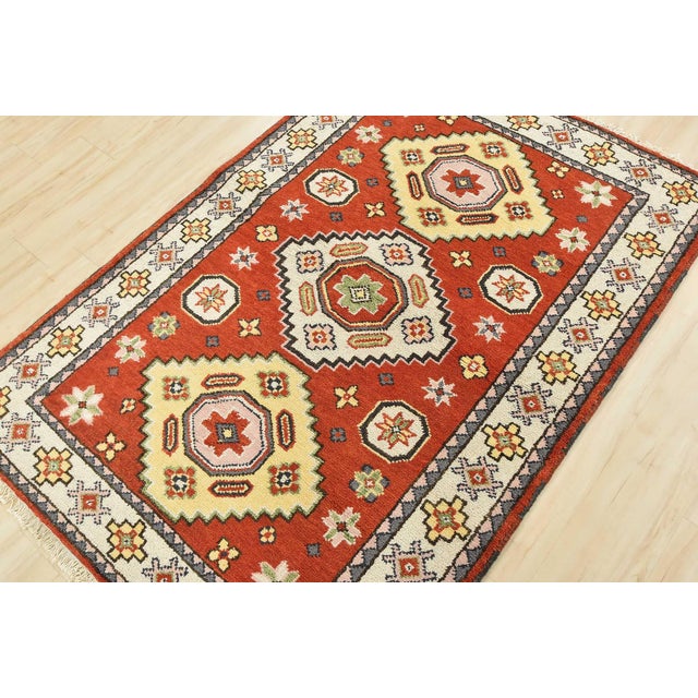 A tribal Caucasian Kazak rug hand-knotted with an all-wool pile on a cotton foundation. This oriental rug features...