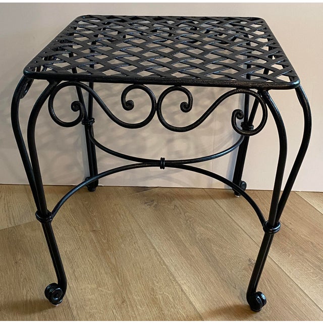 A handsome pair of French-style wrought iron side tables featuring beautifully crafted open lattice tops and elegant hand-...