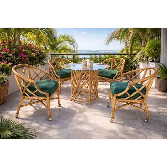 A refined mid-century rattan dining set attributed to Ficks Reed, featuring four barrel-back dining armchairs and a round...