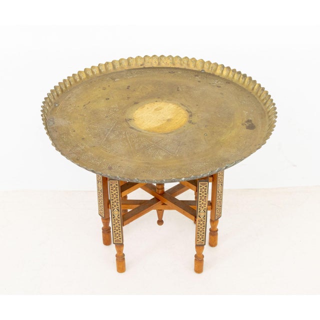 Persian Brass Tray Top Folding Wood Table, the charged with stamped geometric designs. Overall: 19" H x 25" Diameter....